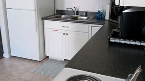 A kitchen with white cabinets, a double sink, a stove, and a refrigerator. - Orchard Lane at Round Lake. (Manitou Beach)
