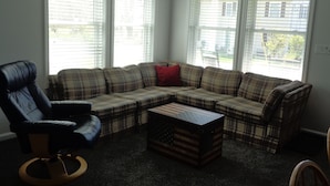 A living room with a sectional sofa, a black leather chair, and a coffee table with an American flag design. - Orchard Lane at Round Lake. (Manitou Beach)