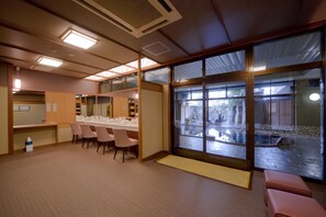 A hotel room with a large sliding glass door, a small sitting area, and a kitchenette.