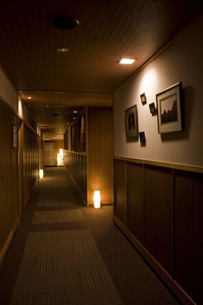 A hotel corridor with wooden paneling, carpeted floors, and framed pictures on the walls.