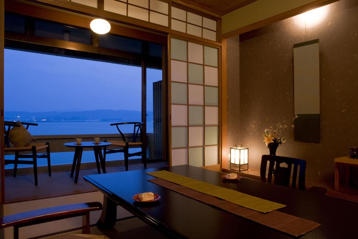 A traditional Japanese room with tatami flooring, a low table, and a view of the sea.