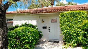 A building with a white door marked with the number 159, surrounded by lush green bushes. - Beachy villa on Siesta Key with heated pool, screened in lanai, and ground level (Sarasota)
