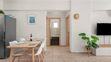 A modern kitchen with a dining area, a TV, and a plant.