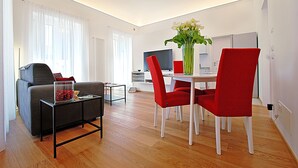En moderne stue med spiseplads, en sofa, et sofabord og en vase med blomster.