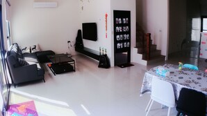 A modern living room with a sofa, coffee table, TV, and a dining area with a table and chairs. - Aegean Sea Homestay (Magong)