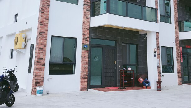 A multi-story building with a modern architectural design, featuring a combination of brick and white walls, large windows, and balconies. - Aegean Sea Homestay (Magong)