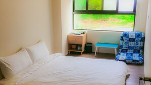 A bedroom with a bed, a small desk, a chair, and a window with a view of greenery. - Aegean Sea Homestay (Magong)