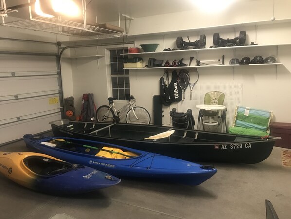 Un depósito con kayaks, una bicicleta y diverso equipo deportivo.