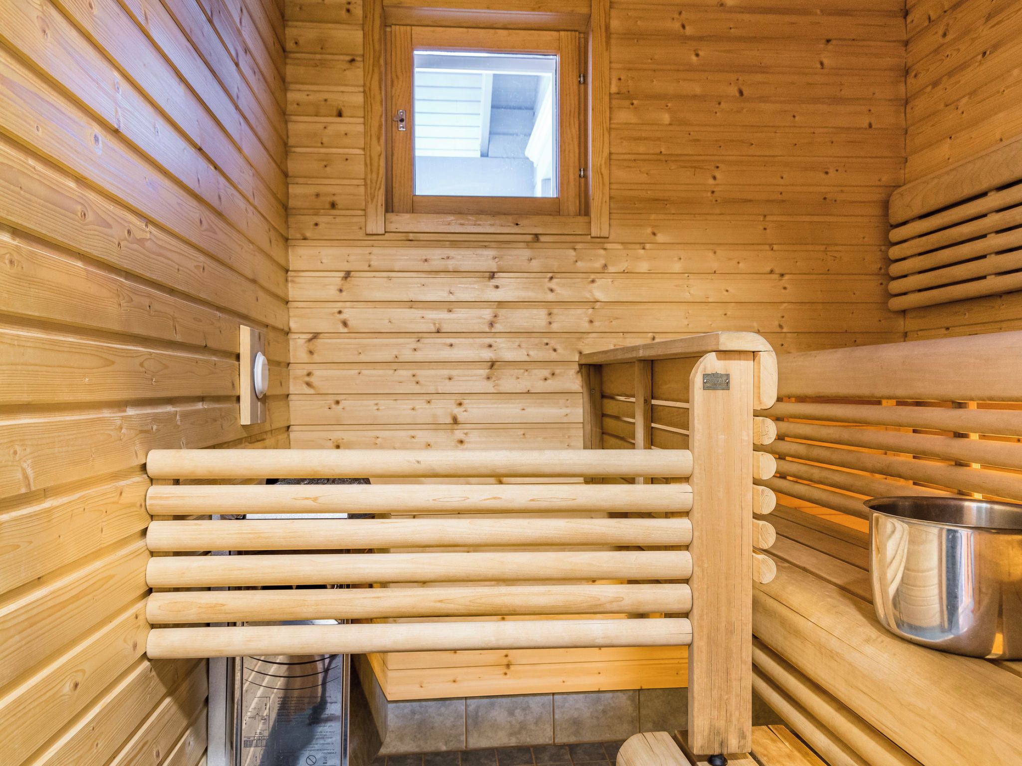 A sauna with wooden walls, a bench, and a metal bucket.