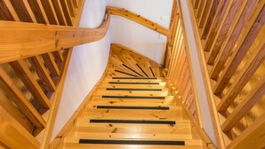 A wooden spiral staircase with a white wall at the top.