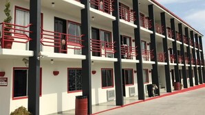 A multi-story hotel with balconies, a red and white color scheme, and a flat roof. - Hotel El Refugio (Tijuana)