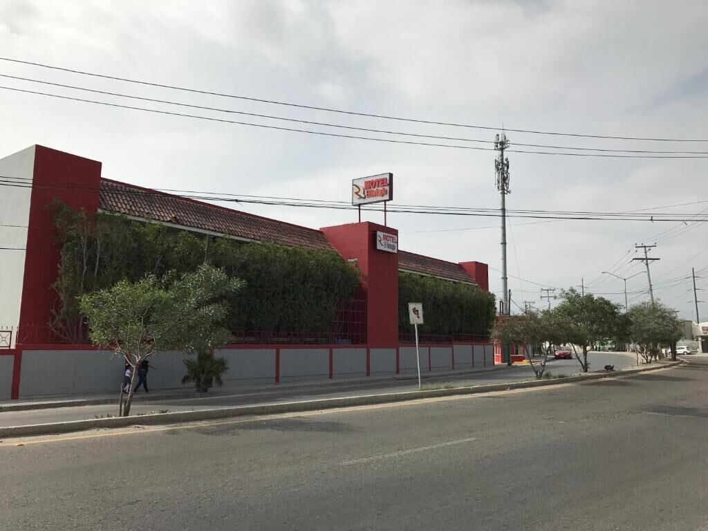 A building with a red and white facade, a sign indicating a motel, and a pedestrian crossing sign.