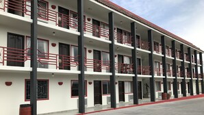 Un hotel de varios pisos con balcones, una decoración en rojo y blanco, y un techo plano.