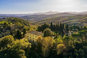 A yellow building surrounded by trees and hills.