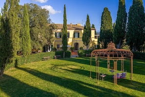 A courtyard with a gazebo, benches, and a building with a tiled roof.