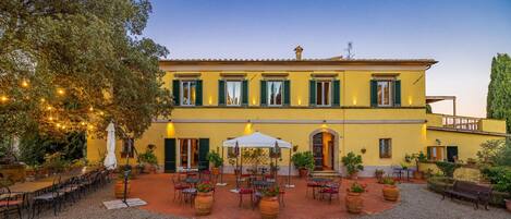 A two-story building with a courtyard, outdoor seating, and potted plants.