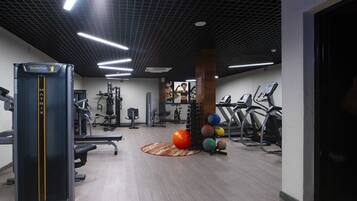 A gym with exercise equipment, a mat, and a wall-mounted machine.