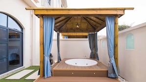 A wooden deck with a hot tub, blue curtains, and a pergola. - NOVOTEL SUZHOU TAI LAKE SANTEH (SUZHOU)
