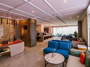 En moderne hotellobby med receptionsdisk, siddeområde og udsigt til elevatoren.