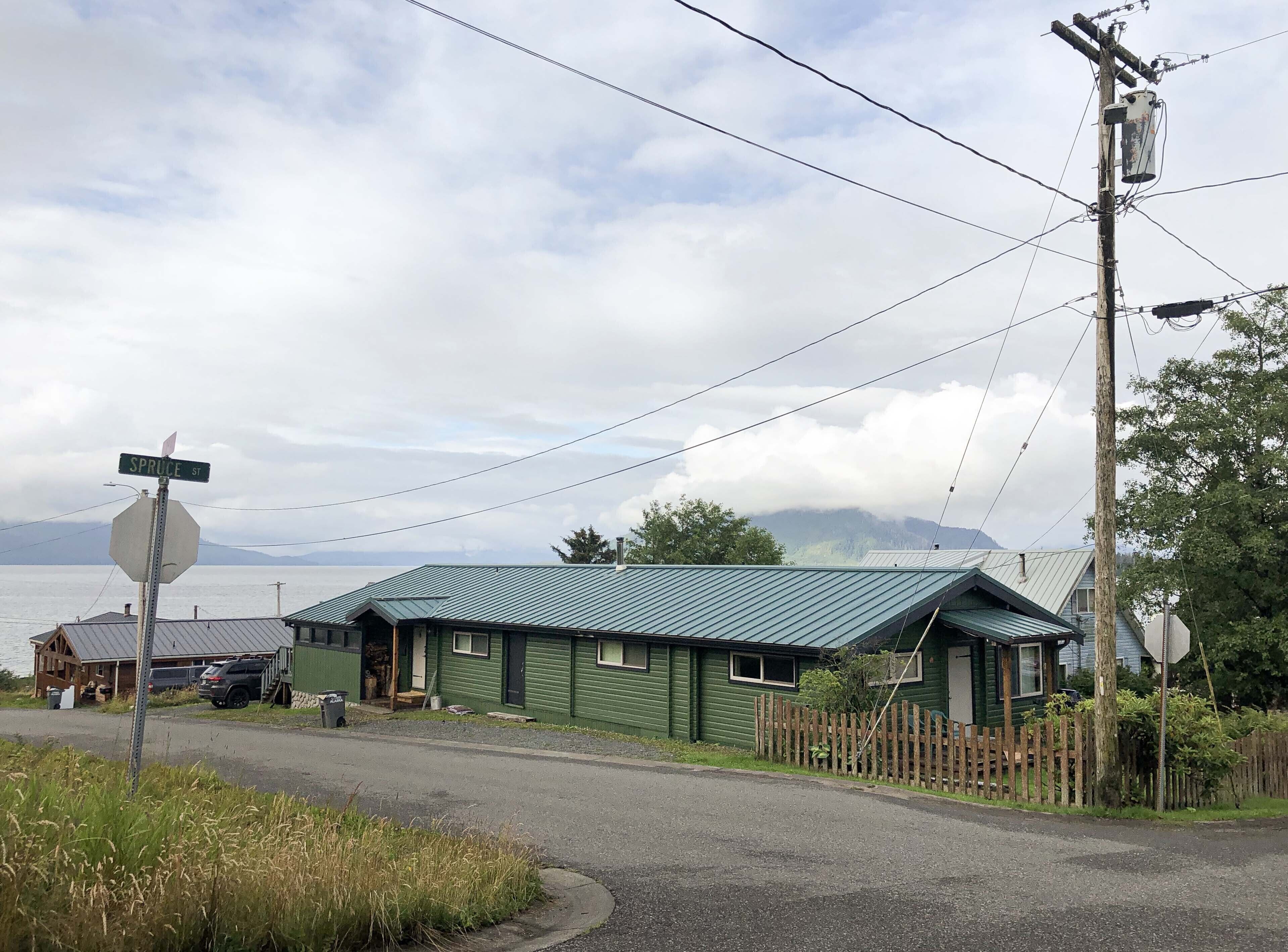 A green building with a metal roof, a stop sign, and a wooden fence.