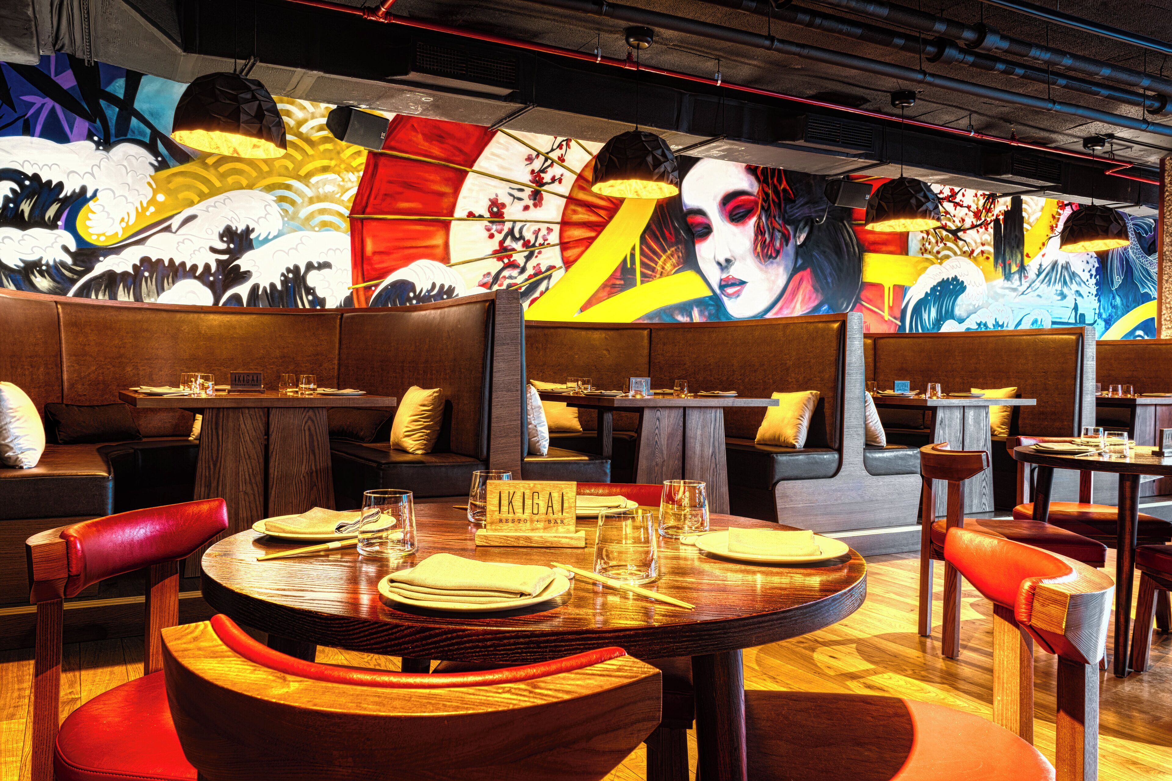 A restaurant with wooden tables and booths, a mural on the wall, and a sign reading "IKIGAI".