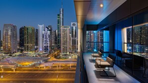 A modern hotel room with a city view, large windows, and a seating area with a table and chairs. - Millennium Place Marina (Dubai)
