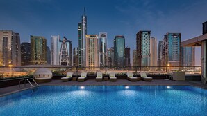 A rooftop pool with lounge chairs and a city skyline in the background. - Millennium Place Marina (Dubai)