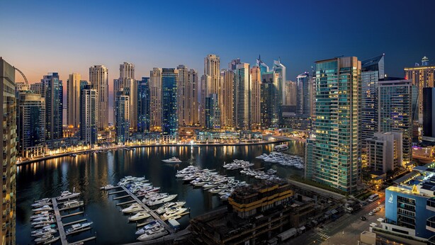 A marina with numerous boats docked, surrounded by high-rise buildings with illuminated windows. - Millennium Place Marina (Dubai)