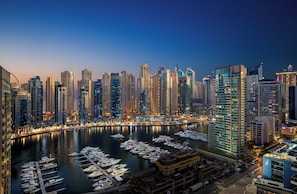 A marina with numerous boats docked, surrounded by high-rise buildings with illuminated windows. - Millennium Place Marina (Dubai)