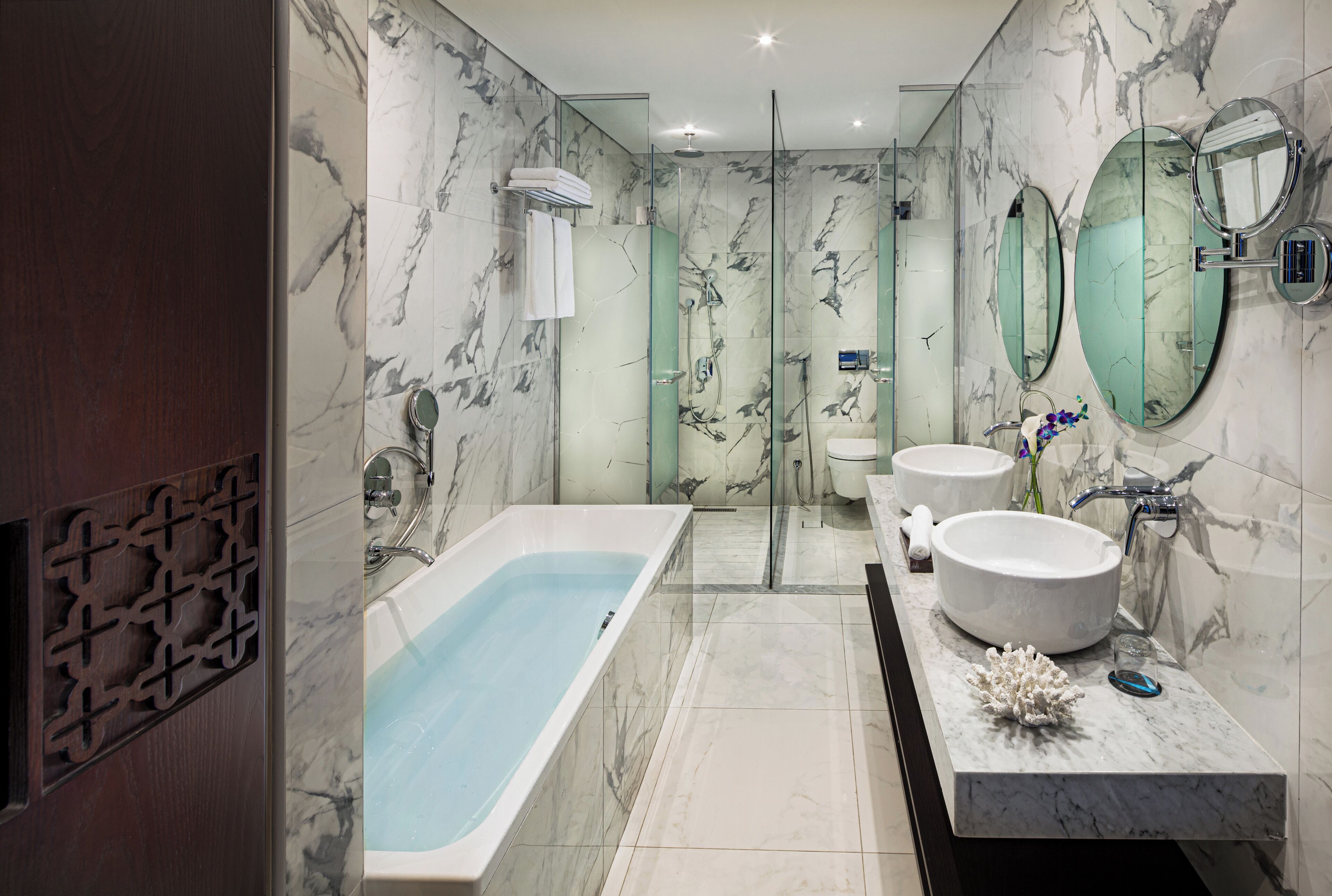Un baño moderno con bañera, dos lavamanos y una cabina de ducha de vidrio.