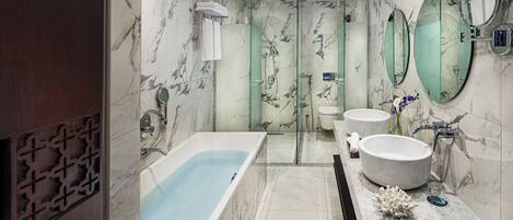 A modern bathroom with a bathtub, two sinks, and a glass shower enclosure.