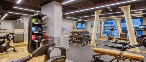 Une salle de sport équipée de machines de cardio, de machines de musculation et d’haltères.