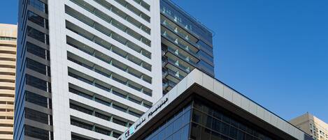 Un hotel moderno con un llamativo letrero que dice 'Millennium Place', que presenta una fachada de vidrio elegante y un diseño estructurado y angular.