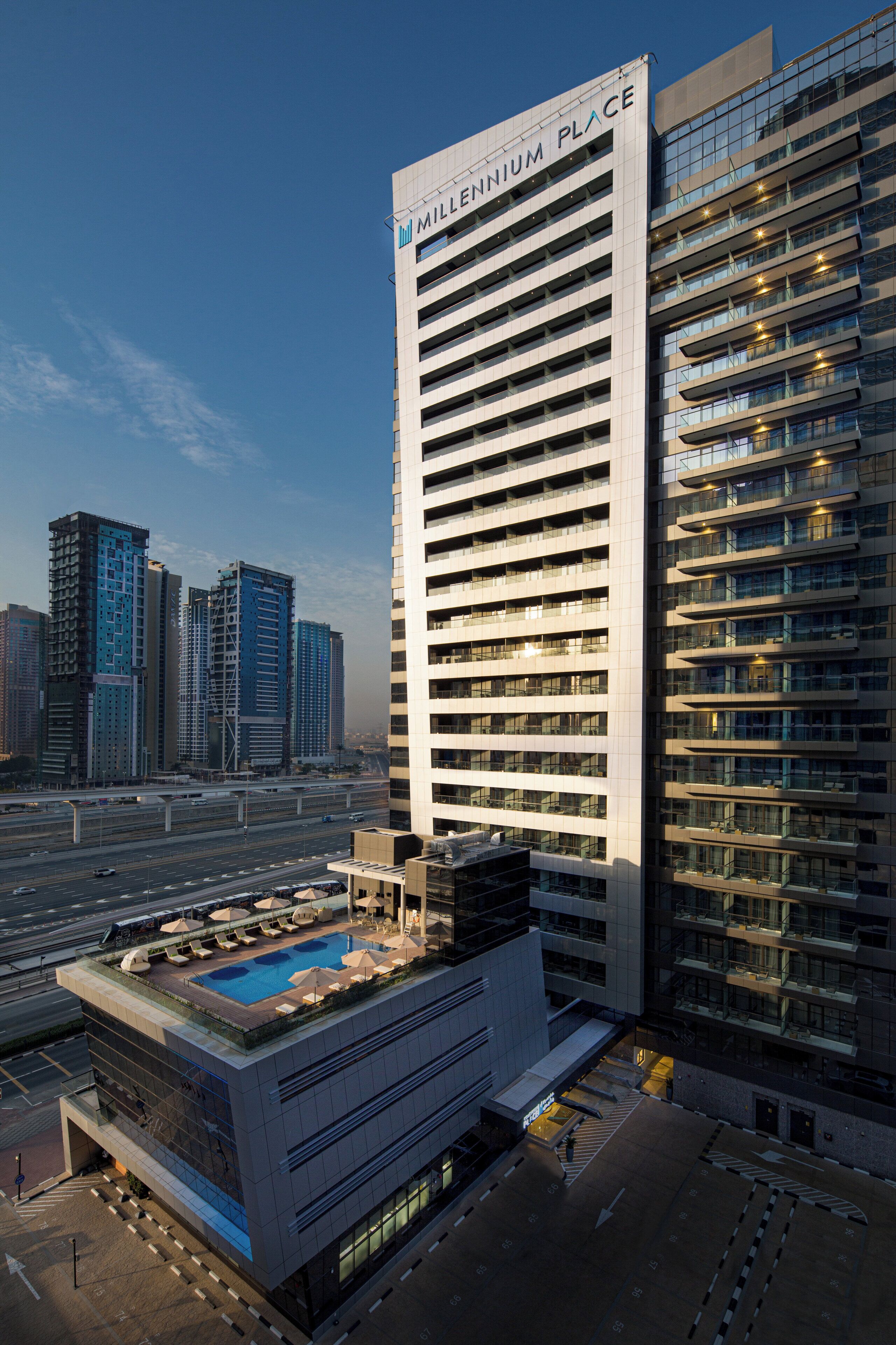 Hotel alto com piscina no terraço e várias varandas.