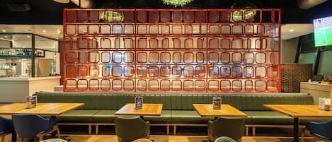 A restaurant interior with booths, tables, and a decorative red wall.