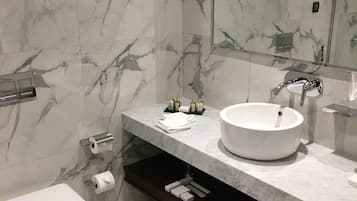 A modern bathroom with a white sink, marble walls, and a toilet.