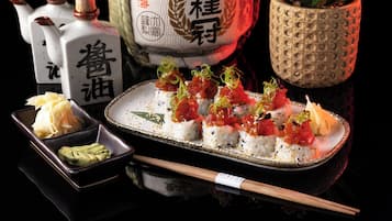 Un plato de sushi con palillos y salsas.