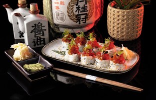 Un plato de sushi con palillos y salsas.