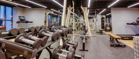 A gym with rows of dumbbells, treadmills, and weight machines.