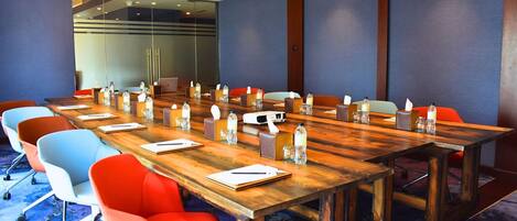 A conference room with a long wooden table, colorful chairs, and water bottles on the table.