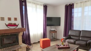 A living room with a fireplace, a television, a sofa, and a coffee table. - Spacious contemporary house with pool and pets allowed (Le Mayet-de-Montagne)