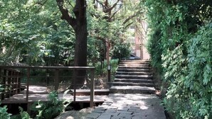 A stone pathway flanked by lush greenery and a wooden fence, leading to a staircase. - JBG Hotspring Resort Hotel (Taipei)