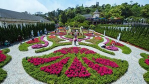 Un jardín formal con arreglos florales simétricos y estatuas.