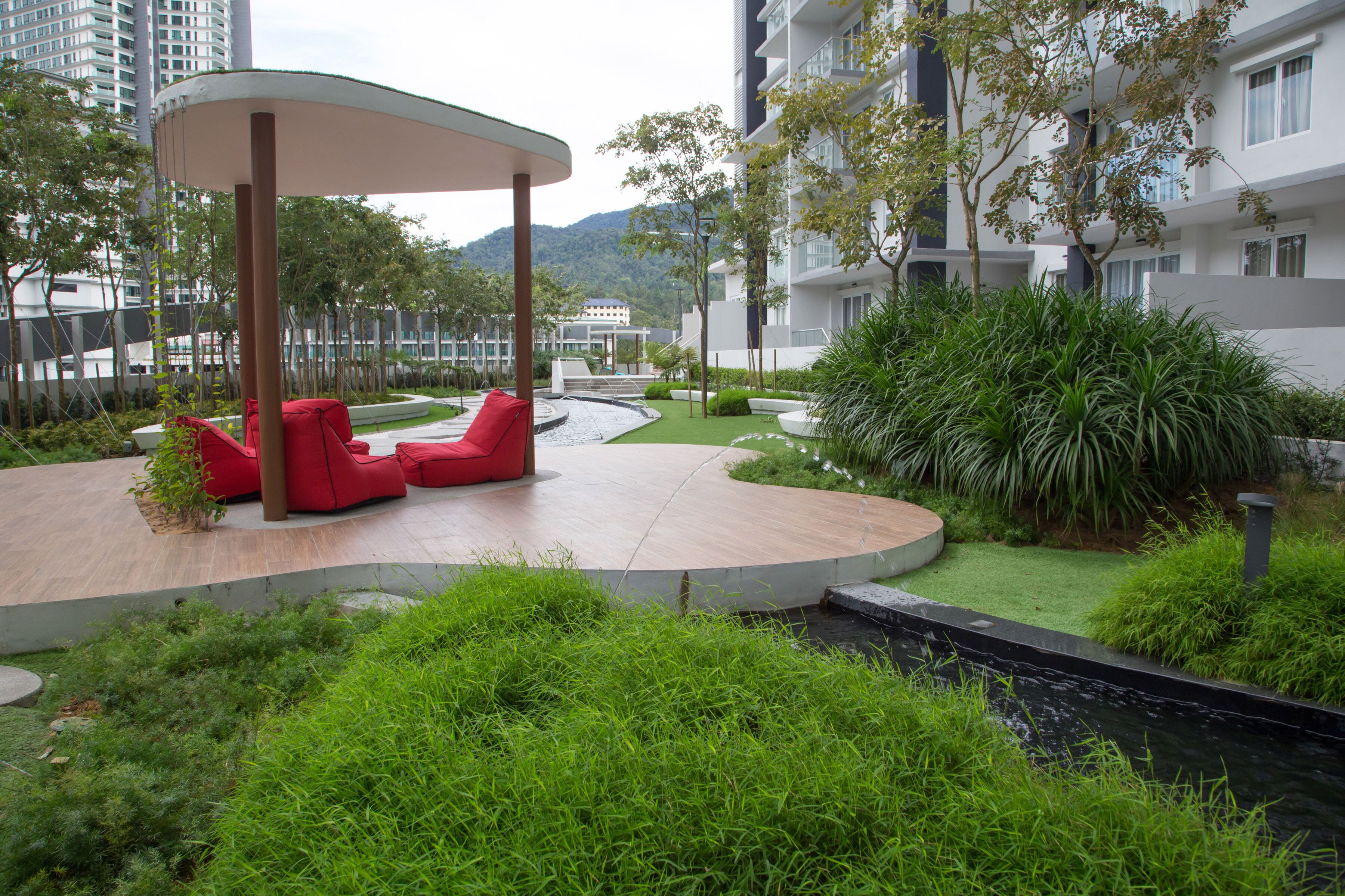 A modern outdoor lounge area with red seating and a water feature.