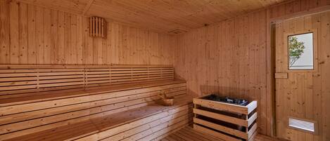 A wooden sauna with benches and a bench seat, a window, and a ventilation system.