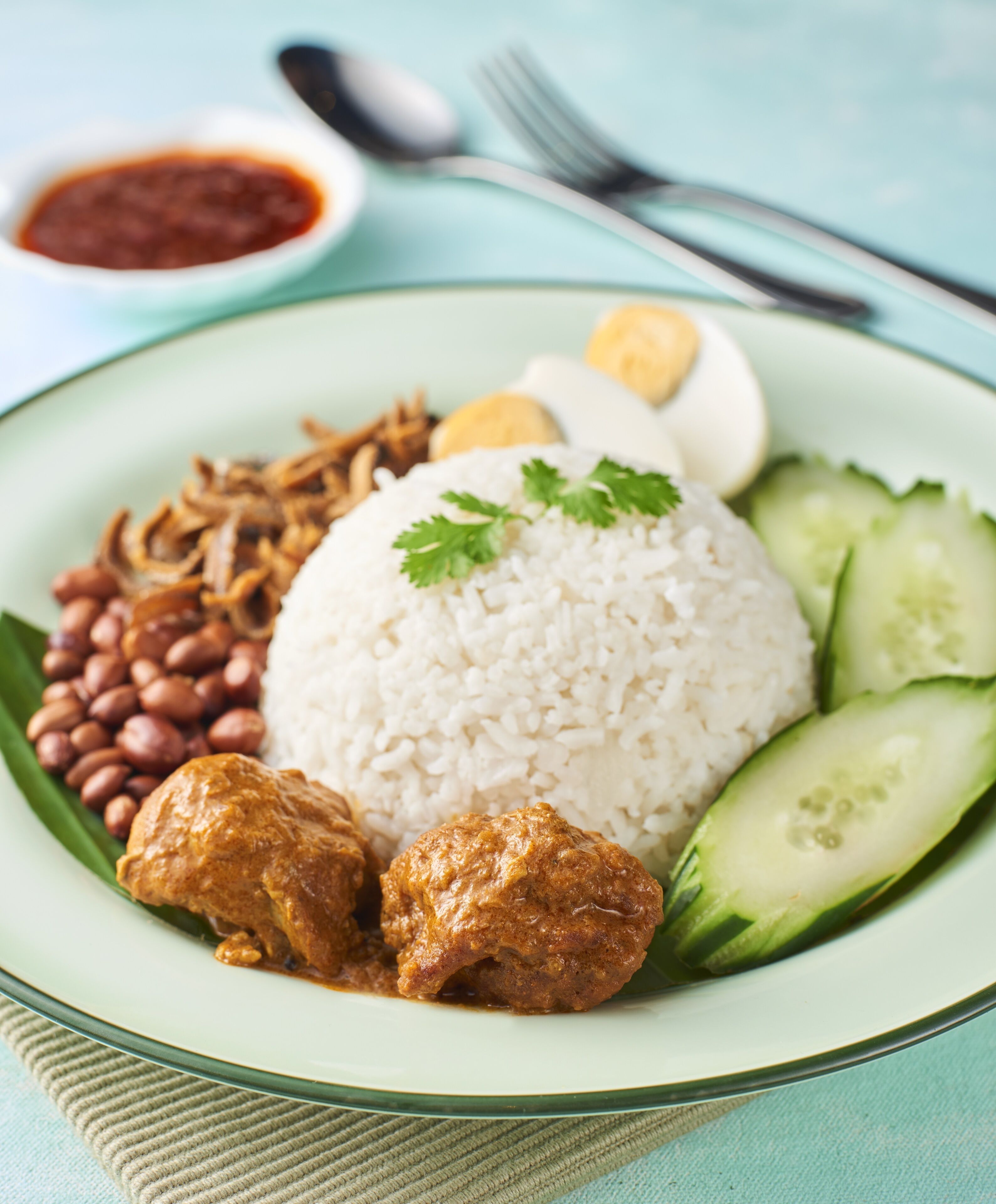 A plate of food with rice, meat, beans, eggs, and cucumber slices.