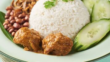 A plate of food with rice, meat, beans, eggs, and cucumber slices.