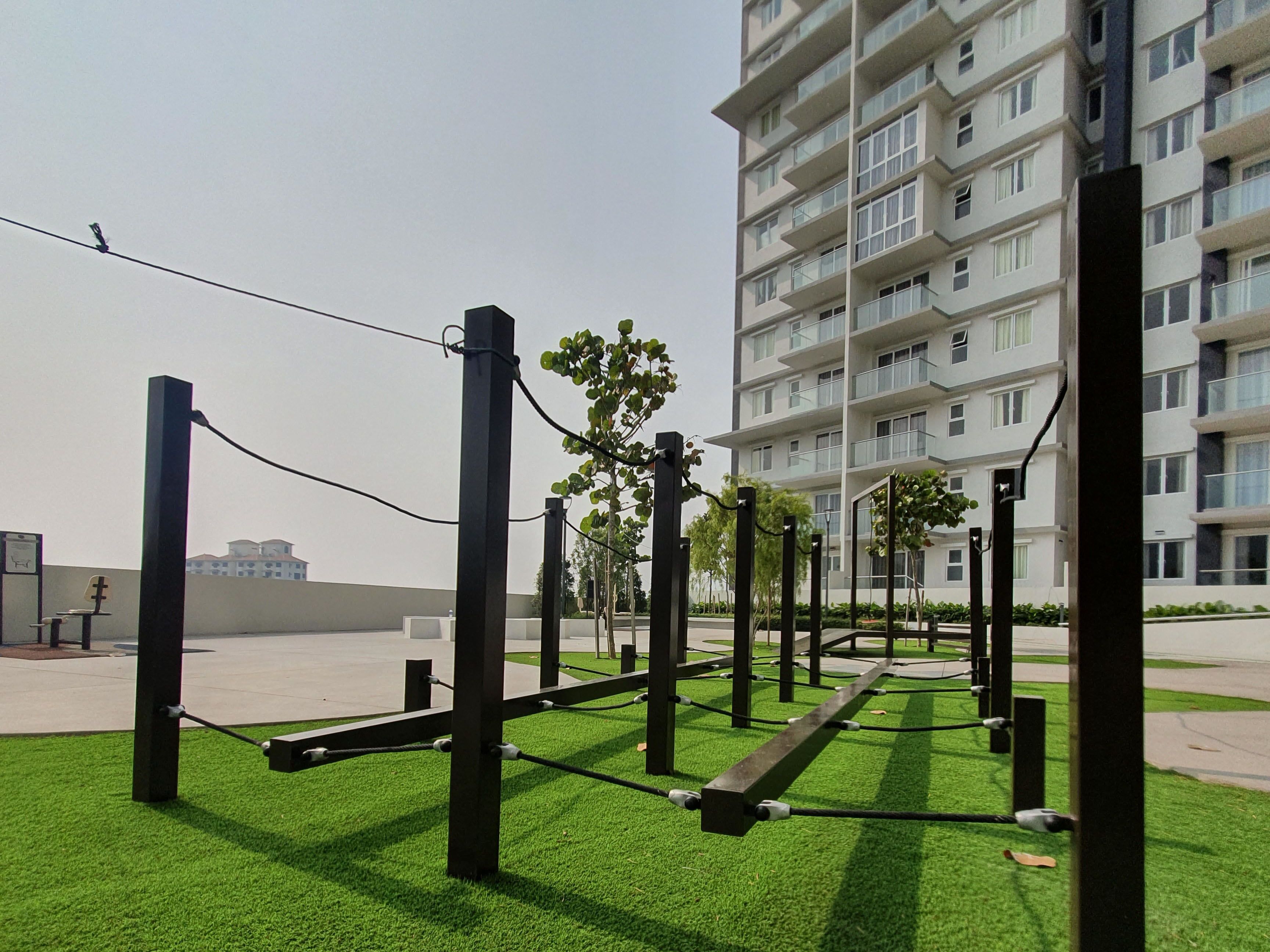 A modern apartment building with balconies, a grassy courtyard, and exercise equipment.