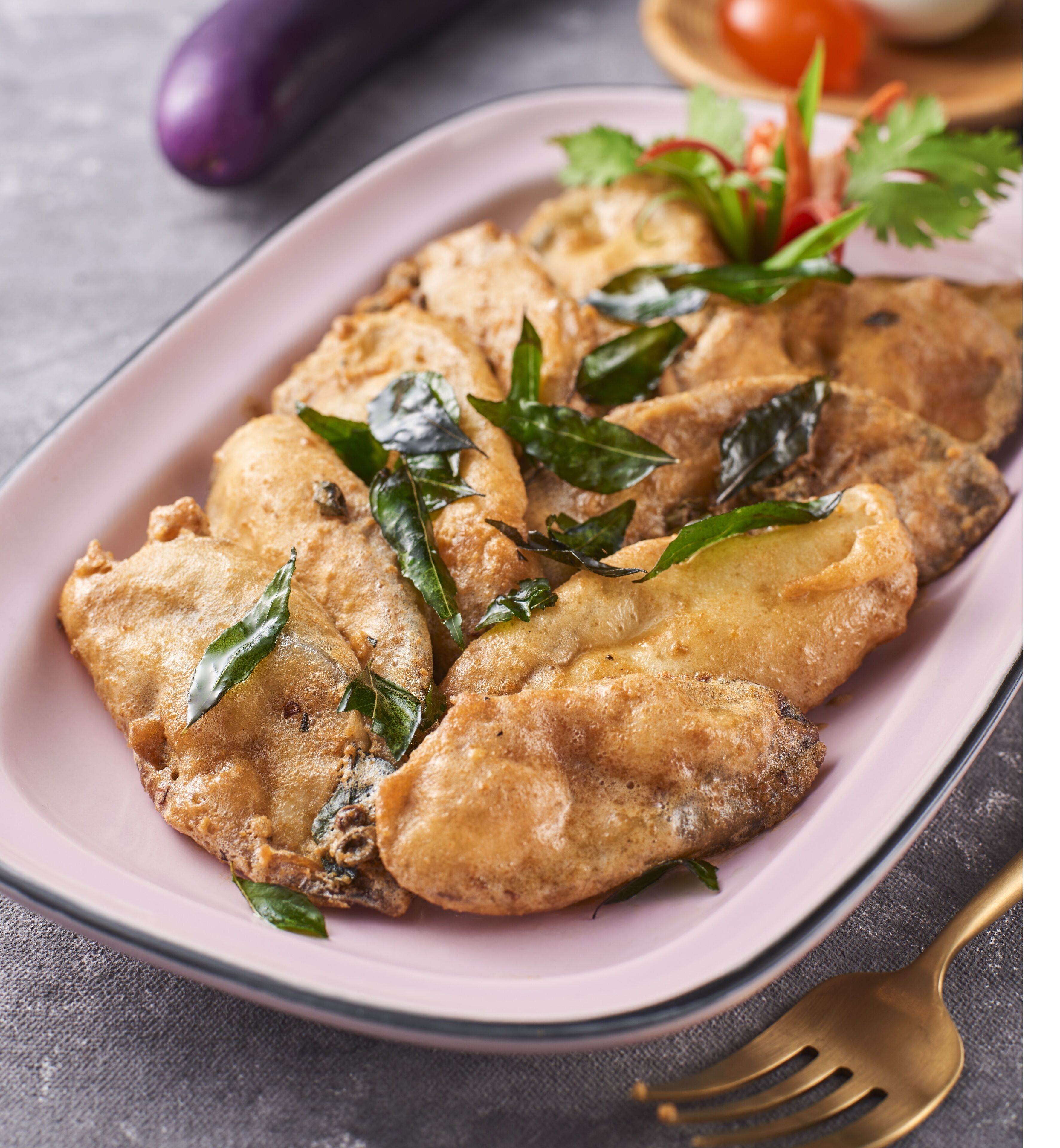 A plate of food garnished with herbs, a fork, and a spoon on a table.