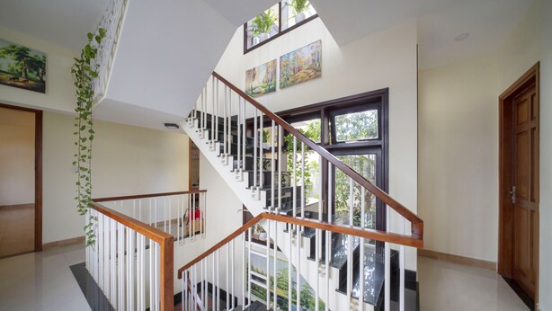 A multi-level interior with a wooden staircase, white railings, and large windows. - Maison Hai Homestay (Da Nang)